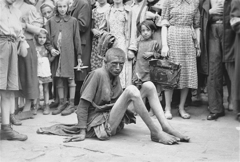 Upokarzająca scena w warszawskim getcie. Głodujący chłopiec w otoczeniu innych Żydów i niemieckiego fotografa, lato, 1941