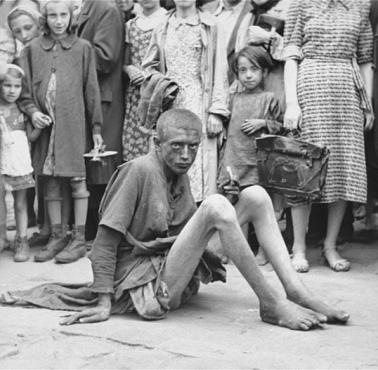 Upokarzająca scena w warszawskim getcie. Głodujący chłopiec w otoczeniu innych Żydów i niemieckiego fotografa, lato, 1941