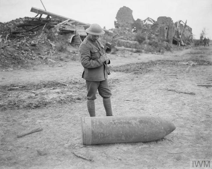 Brytyjski żołnierz stoi obok pocisku artyleryjskiego, Wijtschate, Belgia, 1917