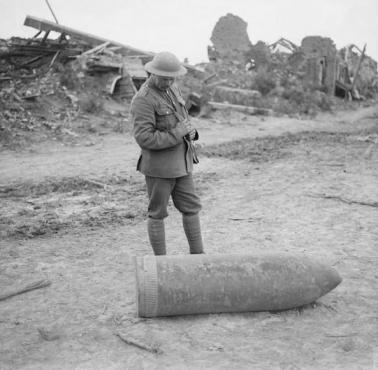 Brytyjski żołnierz stoi obok pocisku artyleryjskiego, Wijtschate, Belgia, 1917