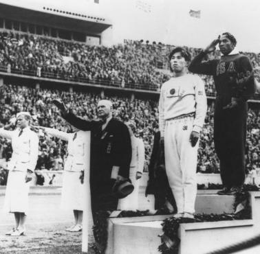 Amerykanin Jesse Owens na podium po wygraniu skoku w dal na Igrzyskach Olimpijskich w Berlinie w 1936 roku