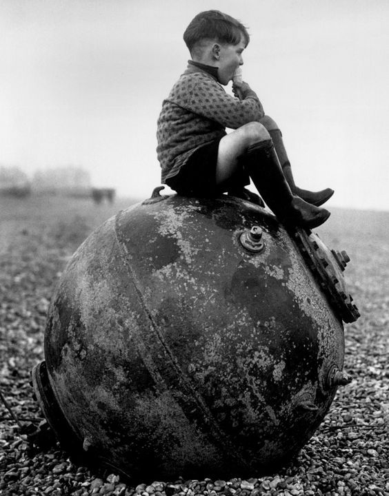 Chłopiec siedzi na rozbrojonej niemieckiej minie, plaża w Kent, Anglia, 1945