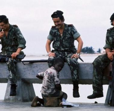 Portugalscy żołnierze śmieją się, podczas gdy dziecko pastuje ich buty, Angola 1972