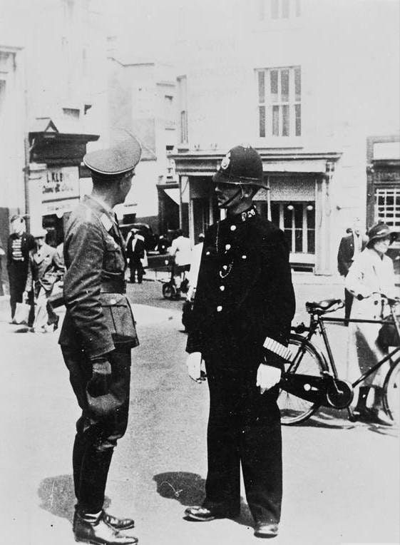 Oficer Luftwaffe rozmawia z brytyjskim policjantem na ulicy Jersey. Wyspy Normandzkie były okupowane przez Niemcy w czasie wojny