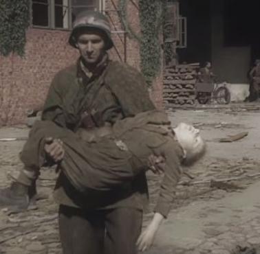 Żołnierz AK niesie na rękach zabitego przez Niemców chłopca, który brał udział w Powstaniu Warszawskim, 1944