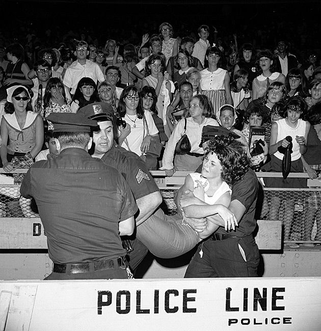 Policja wynosi histerycznie reagujące fanki podczas koncertu zespołu The Beatles w Nowym Jorku (Shea Stadium).