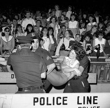 Policja wynosi histerycznie reagujące fanki podczas koncertu zespołu The Beatles w Nowym Jorku (Shea Stadium).