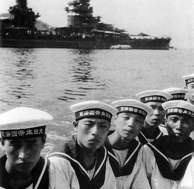 Japońscy marynarze pozują na tle pancernika Fusō (wodowany w 1914 roku, zatopiony w 1944, Kure, Japan).